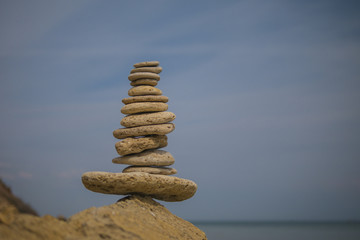 balancing pyramid of stones on a large stone on the seashore