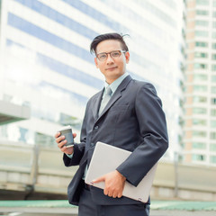 Young Asia handsome businessman drinking hot coffee in the modern city. Breaking and  relaxing business concept