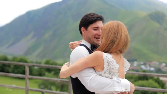 Merry groom and bride against the backdrop of high mountains. The bridegroom is circling the bride. Georgia