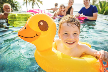 Boy swimming in a pool with family - Powered by Adobe