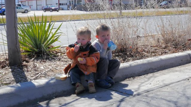 Little Boys eating Luch Sitting on a Curb.