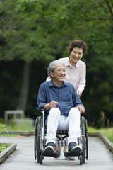 Fototapeta na wymiar 車いすで散歩する老夫婦