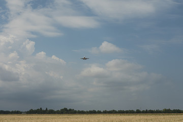 the plane comes on board flying over the field with wheat