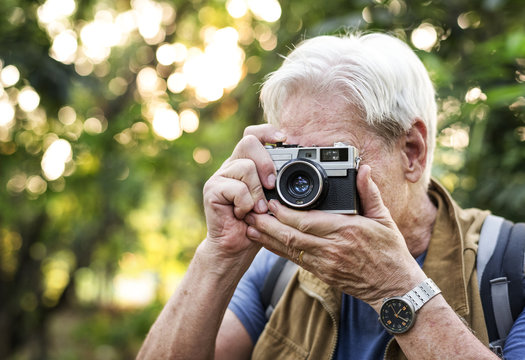 Senior trekker taking a photo with a film camera