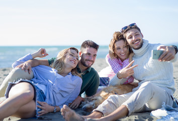 Group of friends having fun on beach during autumn day