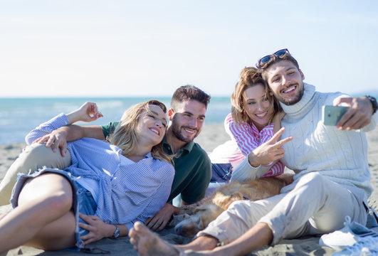 Group of friends having fun on beach during autumn day