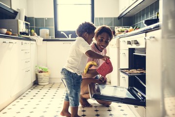 Black kid helping mom baking cookies - obrazy, fototapety, plakaty