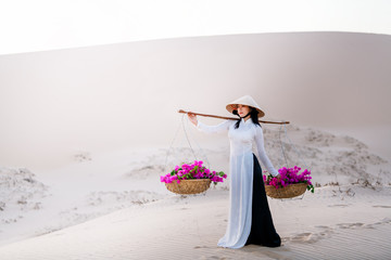 Vietnam woman wearing ao dai culture traditional dress at red sand mui ne during sunrise,mui ne vietnam.