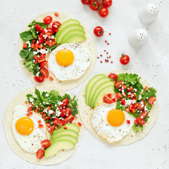 Breakfast tortilla taco with egg, avocado, salsa on bright background, top view, square crop