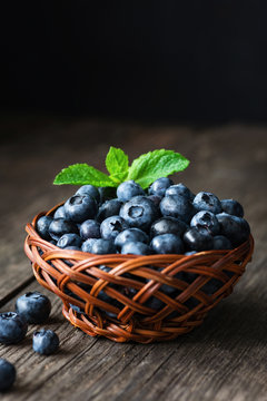Fresh blueberries in a basket on wooden table. Closeup view, selective focus. Berry harvest