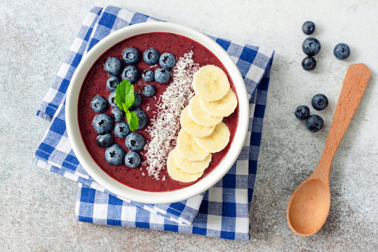 Acai blueberry smoothie bowl with toppings - banana, coconut, blueberries and chia seeds. Healthy eating, healthy lifestyle, vegan diet concept. Top view of smoothie bowl