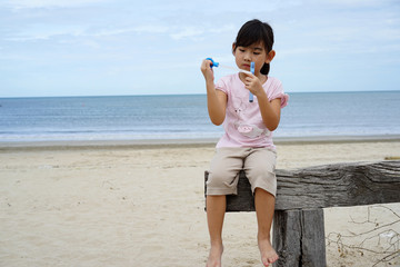 Fototapeta na wymiar Portrait Asian child little girl Blow bubbles Sea background
