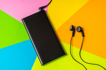Mobile phone with headphones isolated on colorful background