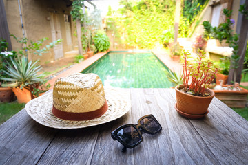 Sunglasses with vintage straw hat fasion on wooden table, Blur background for vintage resort hotel, Concept Summer