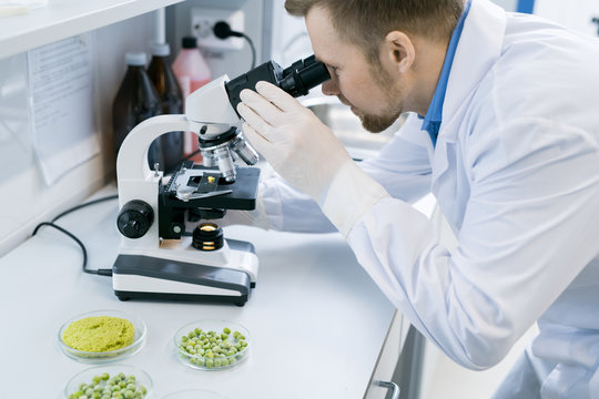 Side view portrait of young scientist looking in microscope while doing research in medical laboratory
