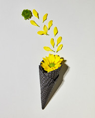 Ice cream bouquet in wafer cone with yellow flower on gray background, flat lay