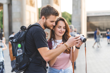 young couple of travelers looking at photo camera at Pariser Platz, Berlin, Germany