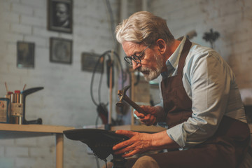 An elderly man in a workshop - Powered by Adobe