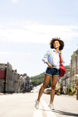 Fototapeta premium Interesting excursion. Beautiful young woman in denim shorts having a tour in a new city and posing for the camera while taking photos