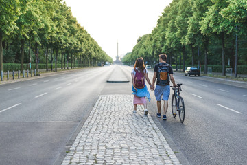 rear view of couple of tourists with bicycle walking at street in Berlin, Germany