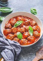 Meatballs with tomato sauce and basil in a white iron pan. Modern style. Dinner concept.