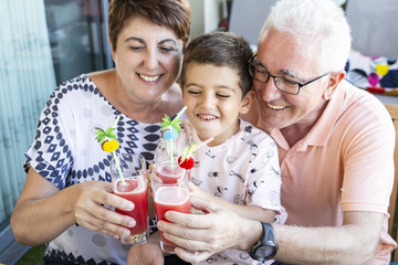 Grandparents and grandson drinking watermelon juice on the terrace in summer