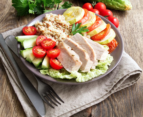 Healthy vegetable buddha bowl lunch with turkey, vegetables and quinoa on brown wooden background. Side view.