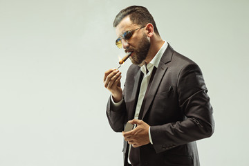 The barded man in a suit holding cigar