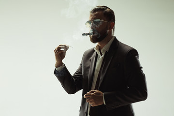 The barded man in a suit holding cigar