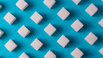Food background with white sugar on blue color paper.