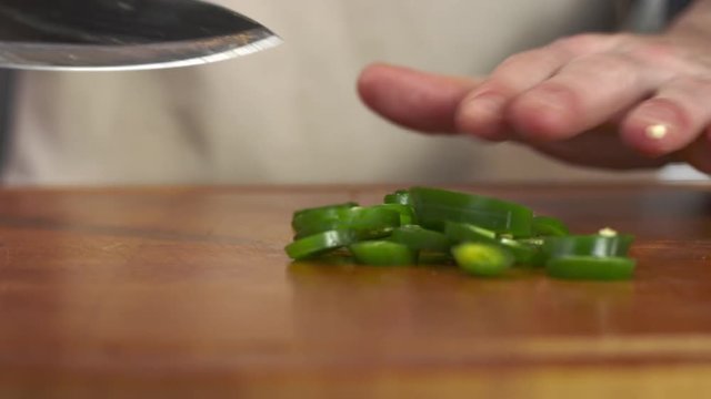 Tracking shot of chef slicing fresh jalapeno pepper