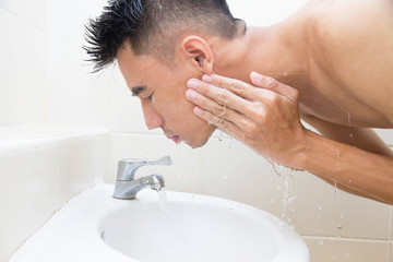 Asian man face wash in bathroom