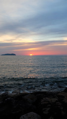 Sunset with orange and red twilight at the horizon, with sea and beach in the foreground