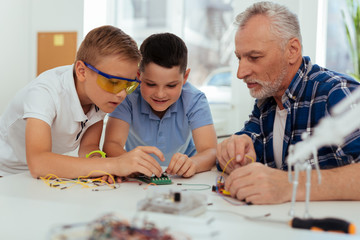 Young engineers. Delighted smart children looking at the microscheme while trying to understand how it works