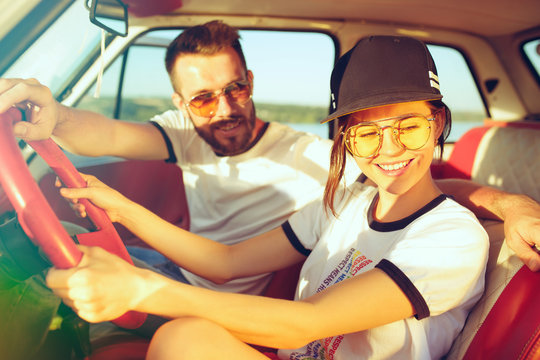 Laughing romantic couple sitting in car while out on a road trip at summer day