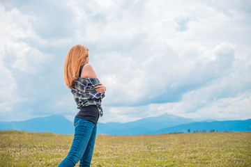 Travel concept, girl traveler looking at clouds and mountains, field. stylish hipster woman , atmospheric moment in adventure. Free lifestyle 