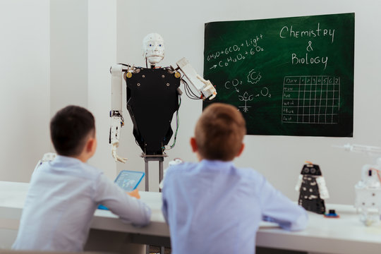 Progressive education. Smart self driven robot standing near the blackboard while conducting a lesson