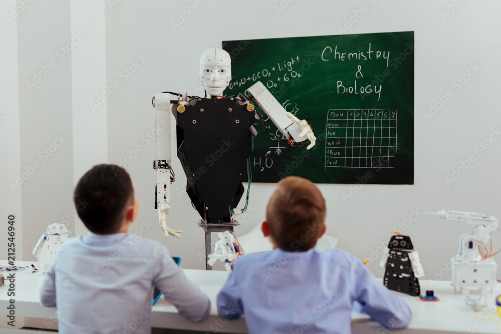 Wall mural schools of future. smart self automated robot looking at the pupils while giving them a lesson