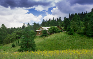 Photo of house in mountain village in the summer under beautiful cloudy sky. Ukraine, Carpathians, Dzembronia