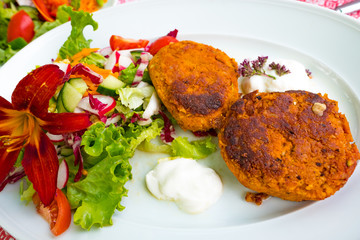 Meatless vegan patties with rolled oats and zucchini served on a white plate with salad and soy yogurt 