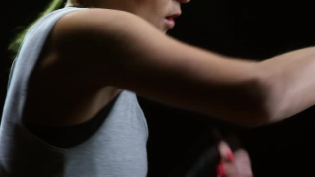 Studio shot with mid-section of female fighter with hands wraps shadowboxing isolated on black background