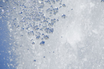 water jet, close-up; large separate drops; white foam in the background