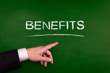 Businessman pointing BENEFITS word on blackboard