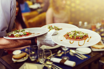 Waiter serving salad at restaurant, close up view