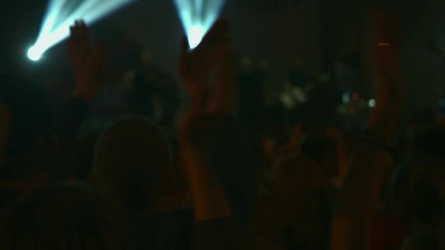 Footage of a crowd partying at a rock concert. Here is footage ot people crowd partying at а concert or а open air. There are dark silhouettes dancing jumping and waving hands. 