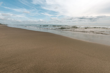 sea wave reach sandy beach under cloudy sky
