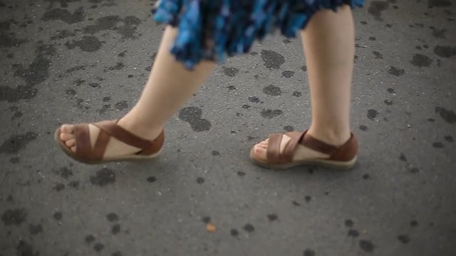 girl goes in comfortable casual shoes on sidewalk, female slender legs