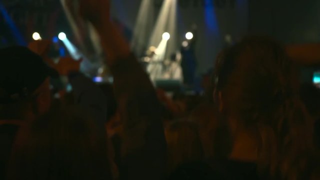 Footage of a crowd partying at a rock concert. Here is footage on people crowd partying at а concert or an open air. There are dark silhouettes dancing jumping and waving hands