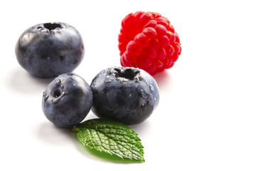 Close-up arrangement mixed, assorted berries including blackberries, strawberry, blueberry, raspberries and fresh leaf on white