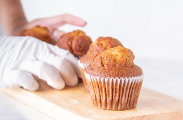 Side view close up brown muffin or banana cake on white table and hands background for breakfast in morning day.